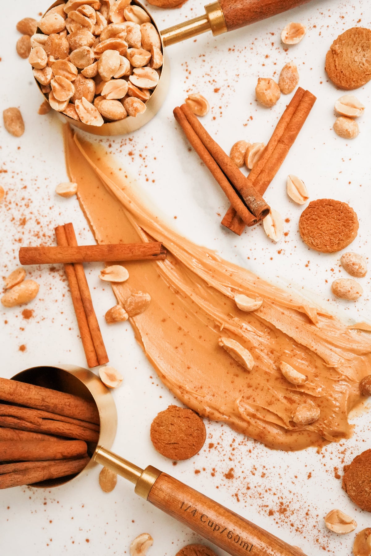 Cinnamon and peanut butter on a white surface with measuring spoons.